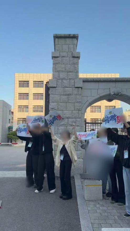 휘문중학교 정문에서 팔을 들어 수험생을 응원하는 수능하루 운영진