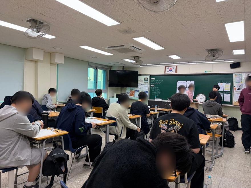 감독관이 칠판 앞에서 시험 유의사항을 안내하는 고사실